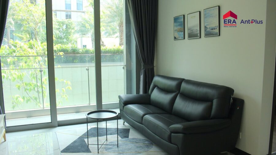 Phòng khách căn hộ Tilia 1 phòng ngủ với sofa da đen và cửa kính ra sân vườn