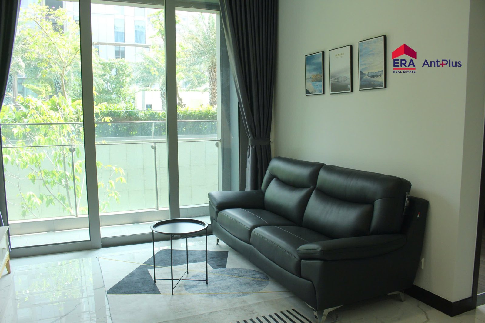 Phòng khách căn hộ Tilia 1 phòng ngủ với sofa da đen và cửa kính ra sân vườn