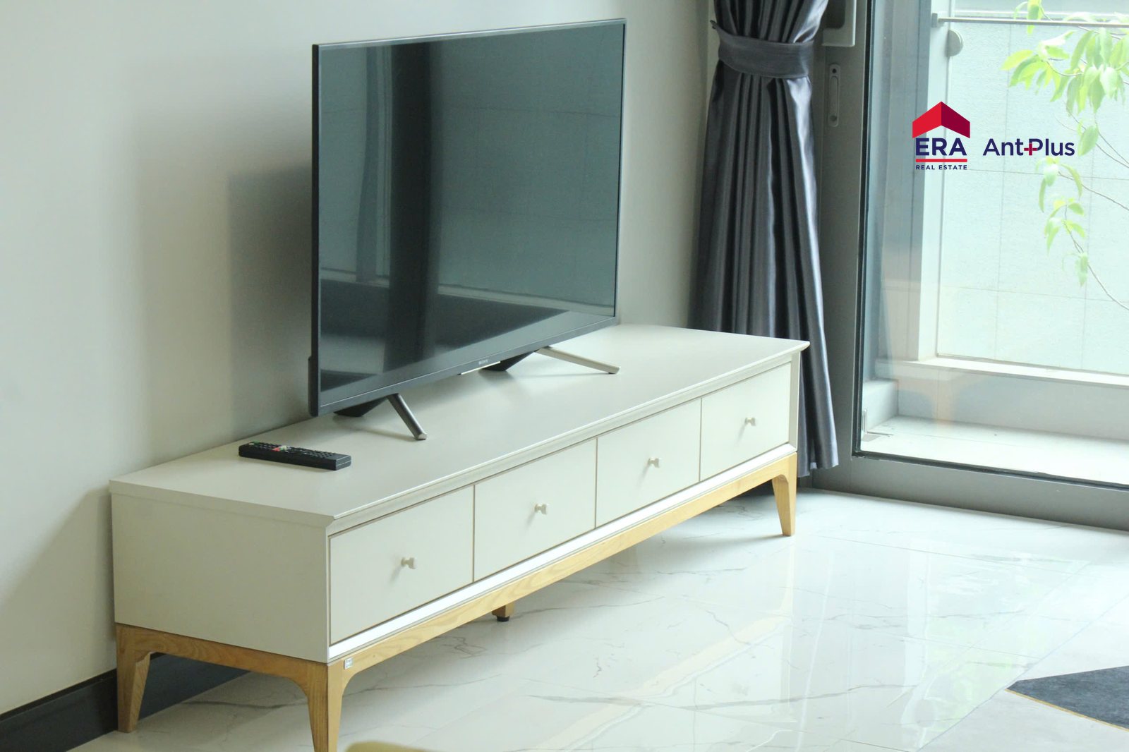 Kệ TV trắng chân gỗ trong phòng khách căn hộ Tilia