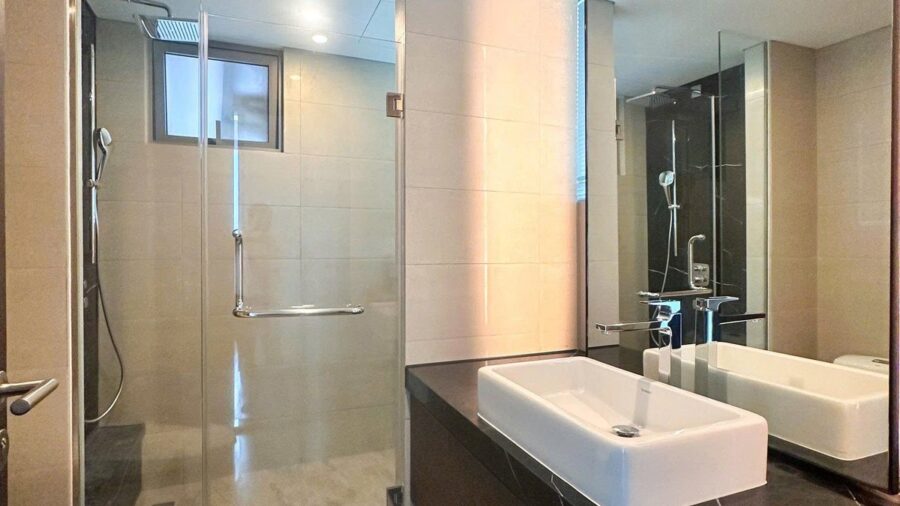 Phòng tắm căn hộ Tilia với vách kính và lavabo trắng