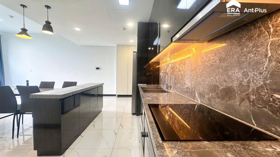 Đảo bếp mặt đá vân nâu và bếp từ căn hộ Tilia