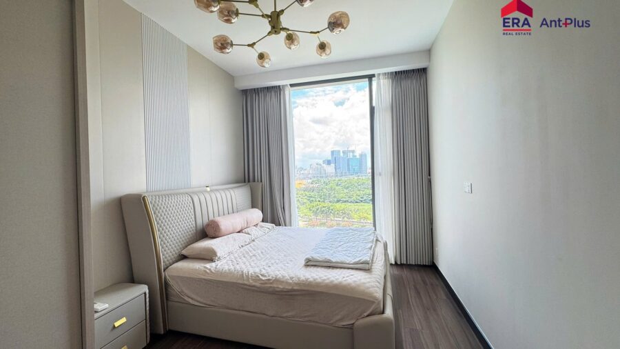 Phòng ngủ căn hộ 1PN Linden có giường bọc nệm và đèn chùm