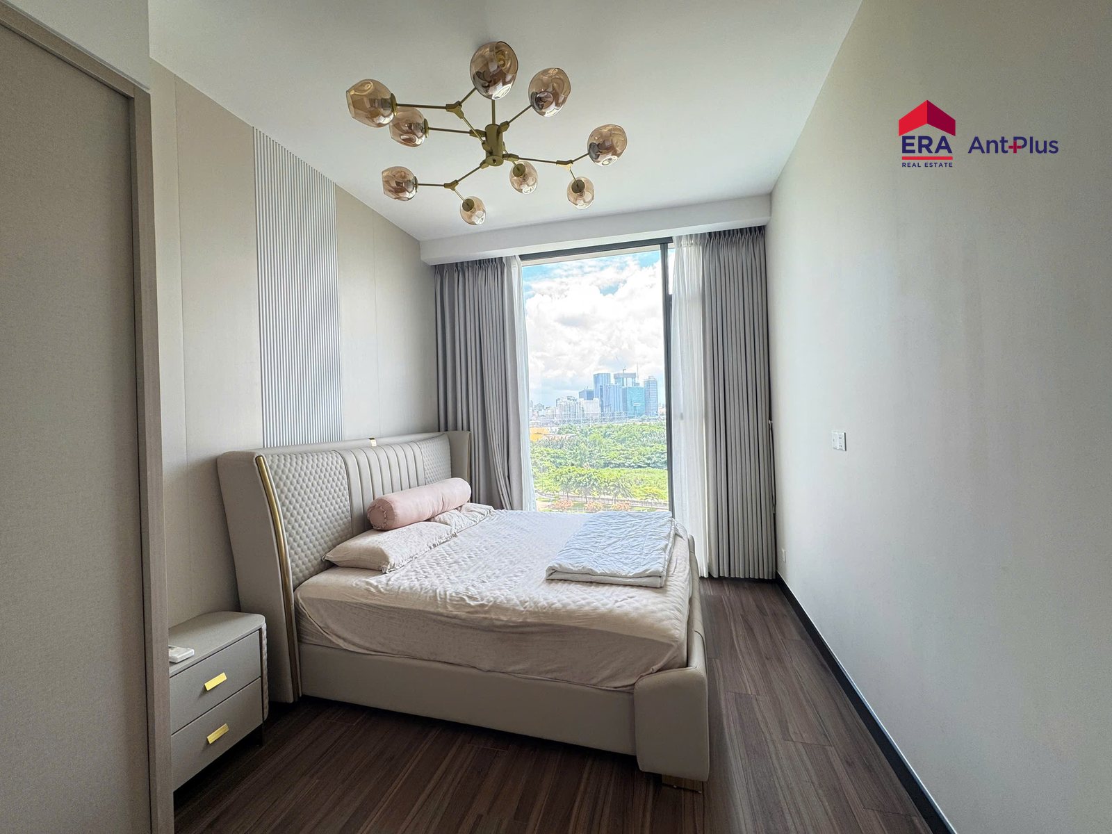 Phòng ngủ căn hộ 1PN Linden có giường bọc nệm và đèn chùm