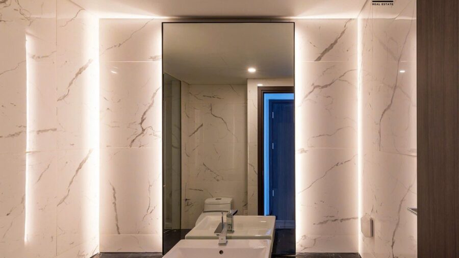 Lavabo đá đen và gương đèn hắt trong phòng tắm căn hộ Linden