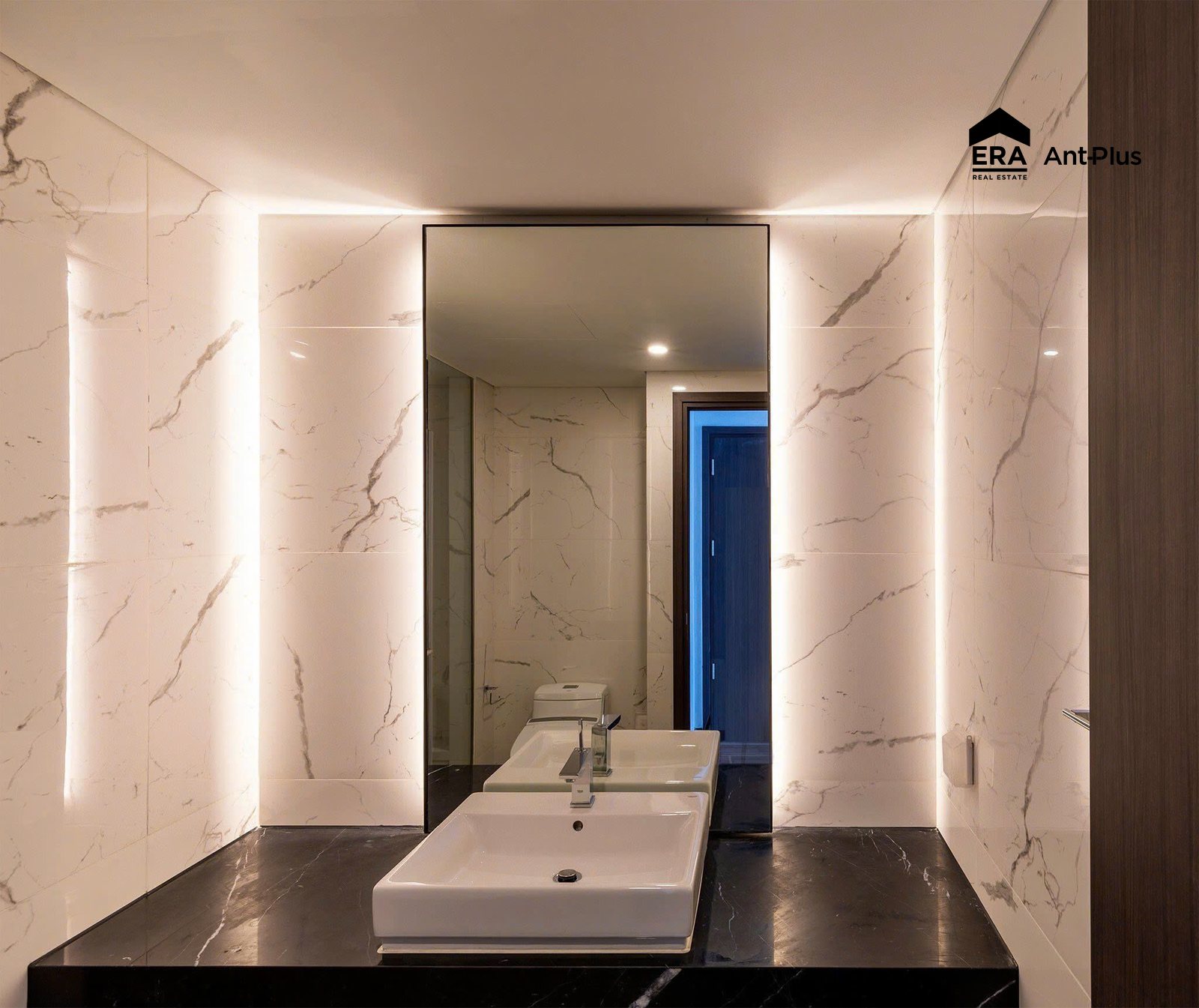Lavabo đá đen và gương đèn hắt trong phòng tắm căn hộ Linden