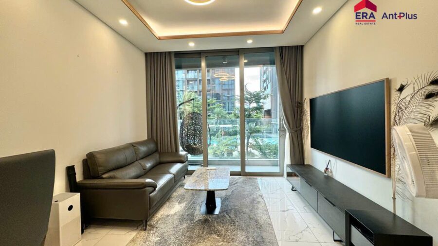 Phòng khách với TV lớn và thảm xám căn hộ Tilia tầng 3