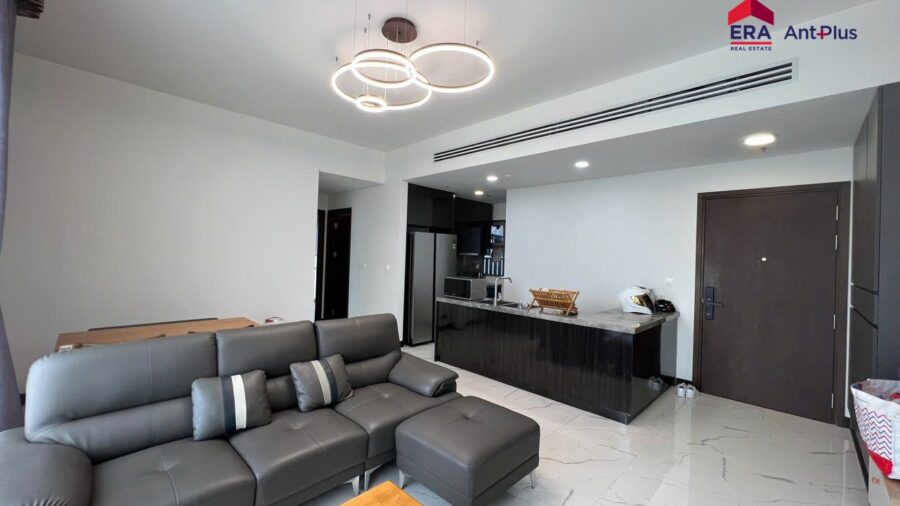 Sofa góc xám nhìn về bếp và cửa chính căn hộ Tilia 90m2