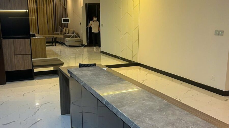 Đảo bếp mặt đá xám và hành lang phòng khách căn hộ 2PN Tilia